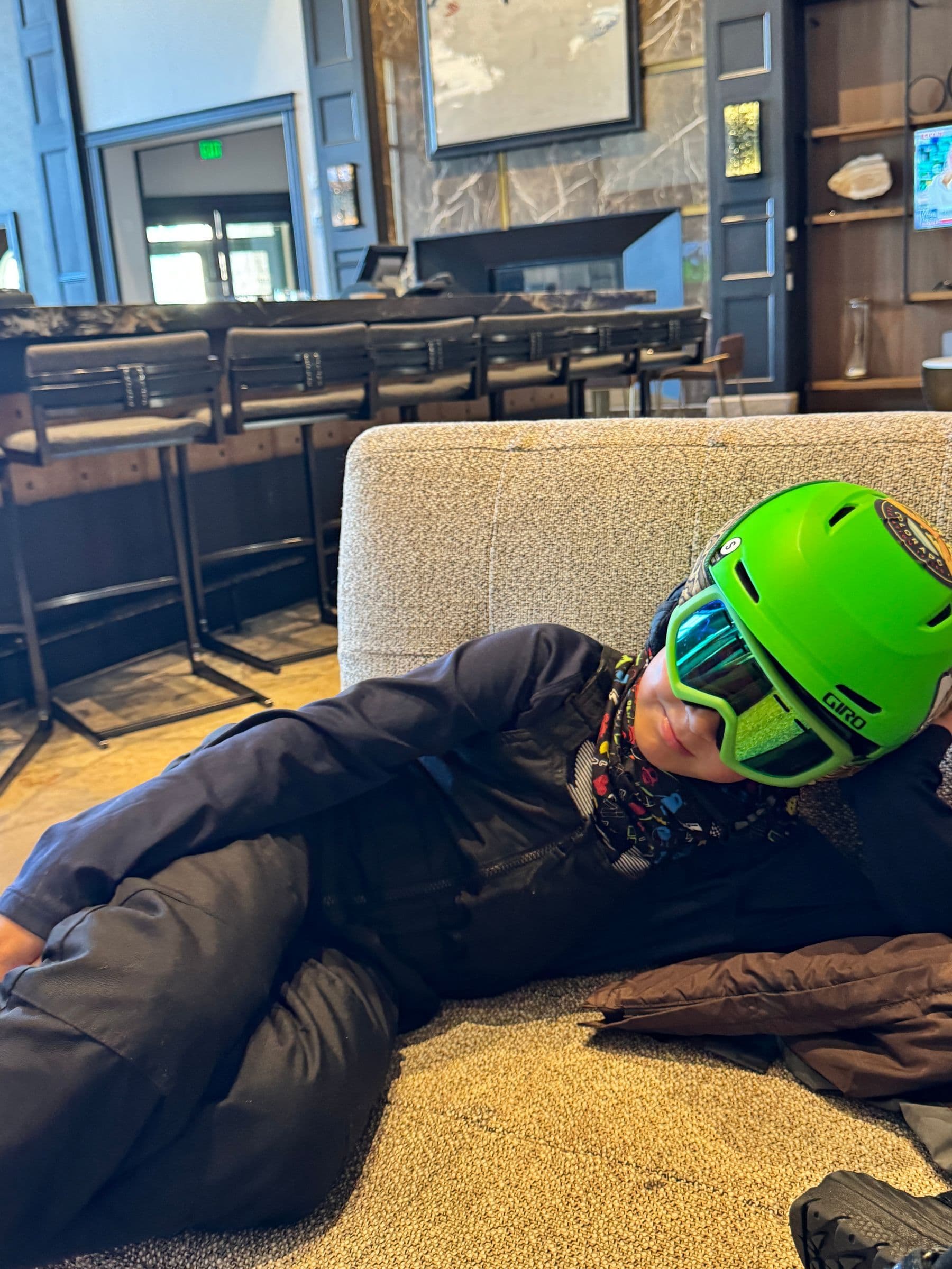 Boy in snow gear with lime green helmet and green ski goggles