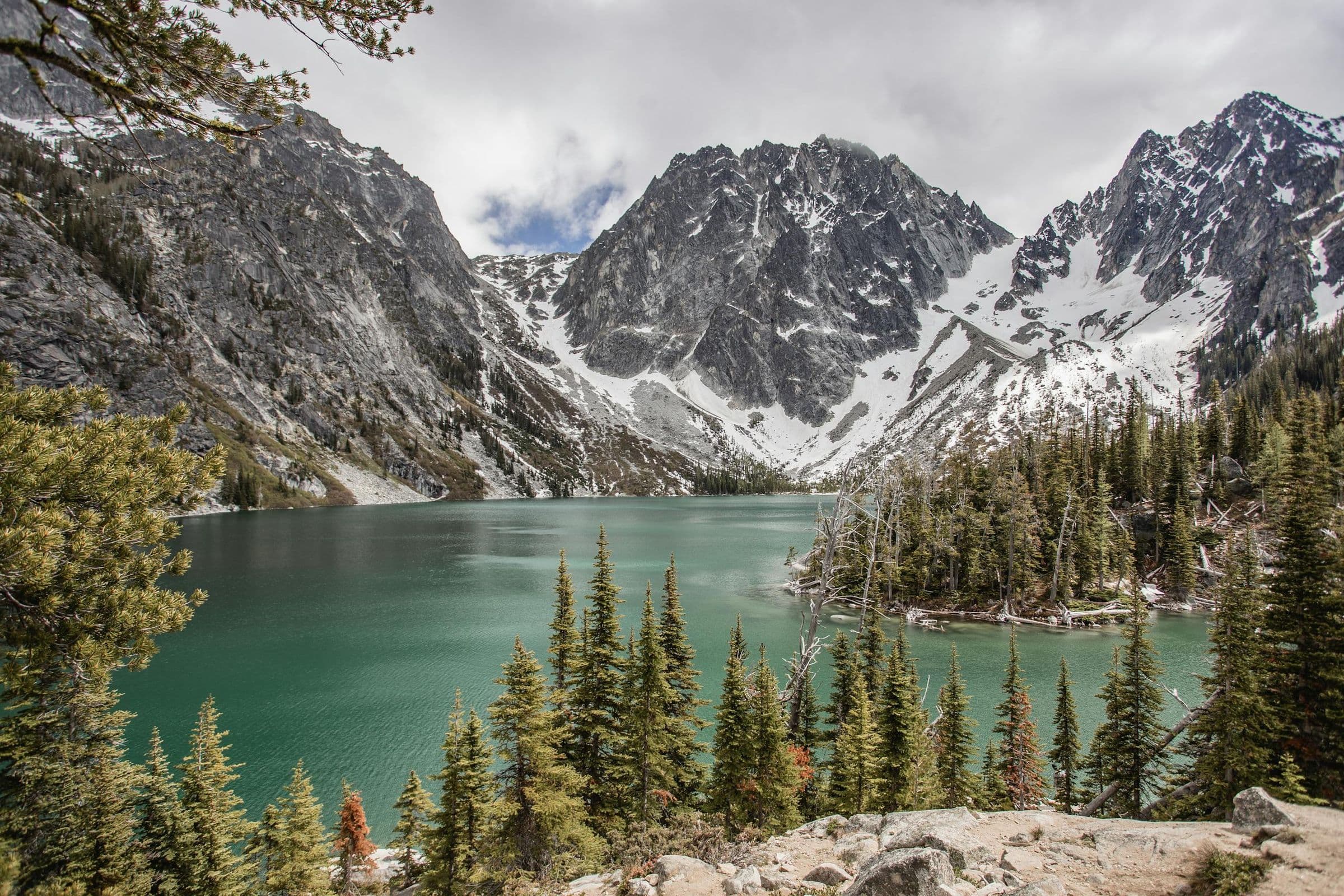 Breathtaking view of Colchuck Lake with snow-capped mountains and lush trees in Washington.