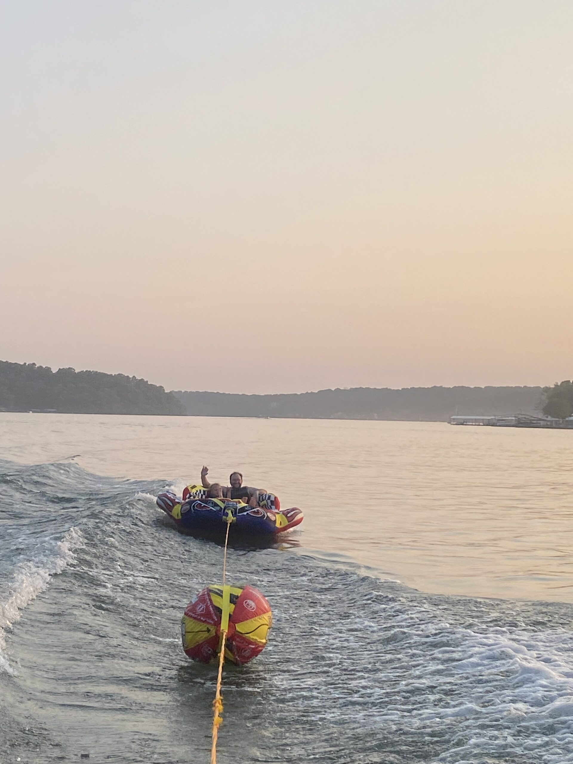 Dad and son on the back of a Tube at Lake of the Ozarks water at sunset