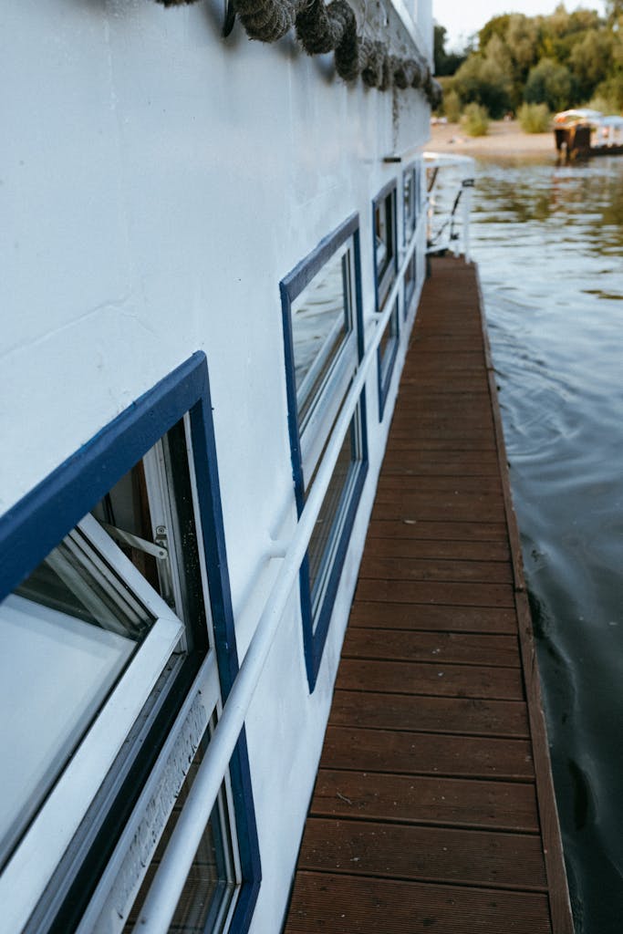 A calming scene of a boat's deck with windows alongside a peaceful lake.